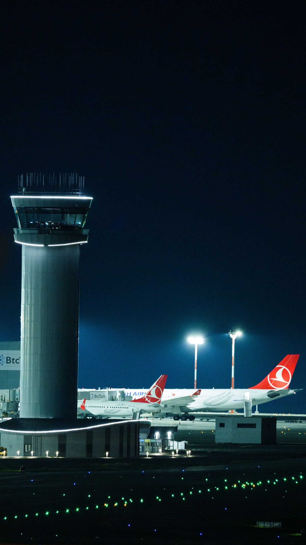 Illuminated airport control tower and aircraft at night - Jhears Aerospace contact page